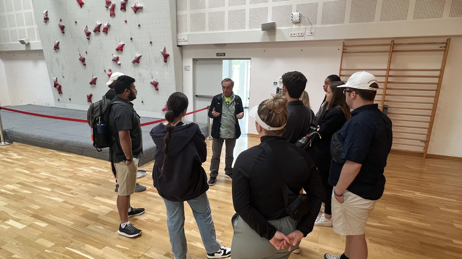 Student stand in front of climbing wall