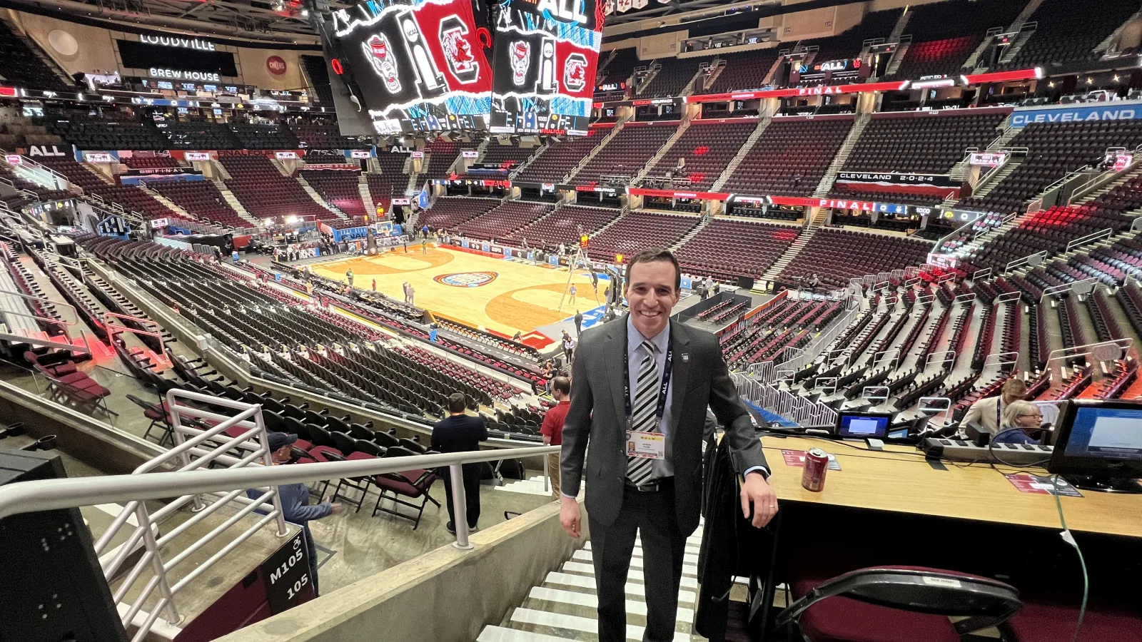 Man stands on stairs with basketball court behind him