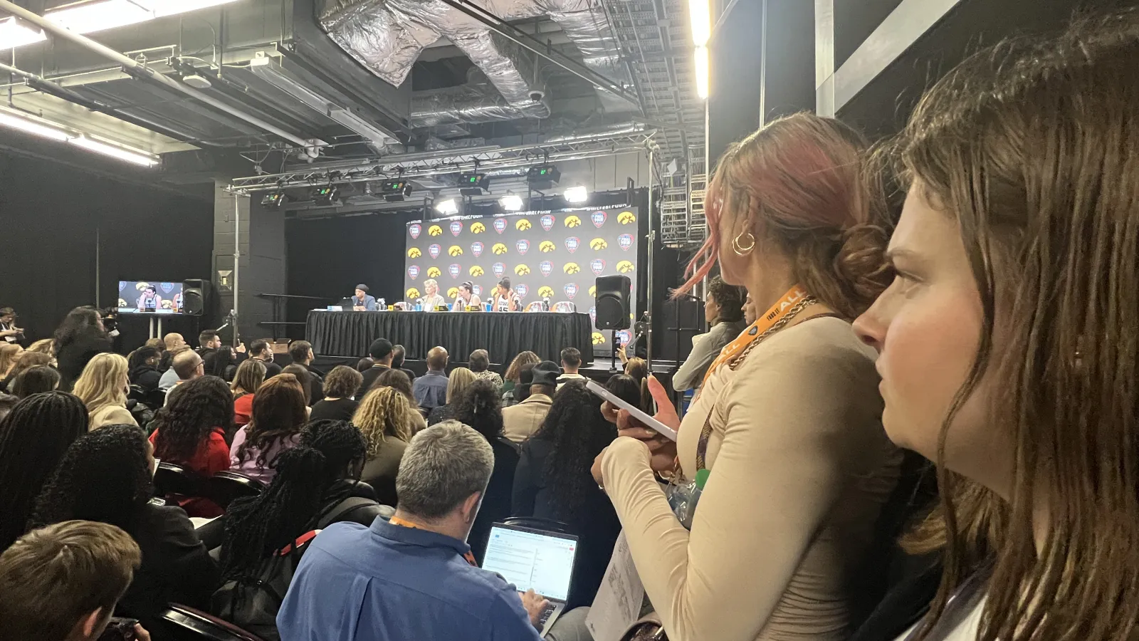 Woman standing at press conference with people and stage