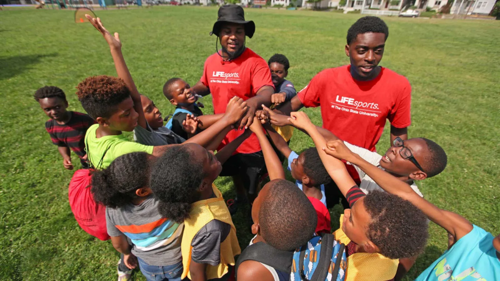 kids in a circle on grass with two camp counselors