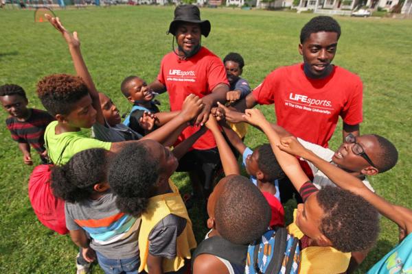 kids in a circle on grass with two camp counselors