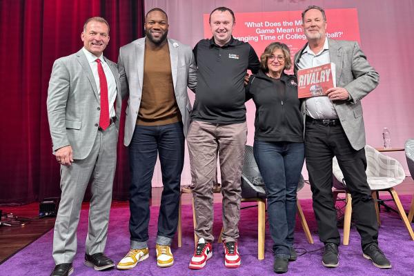 Four men and one woman posing on a stage